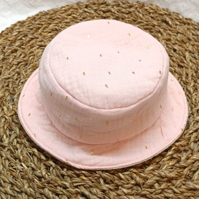 Chapéu rosa claro com detalhes dourados sobre tapete trançado