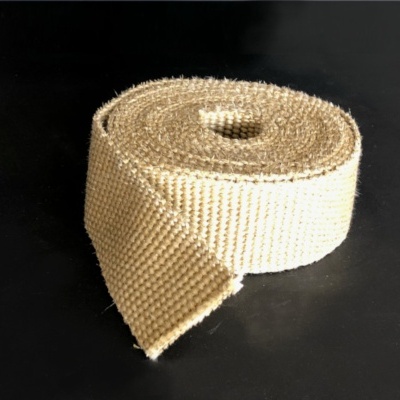 Rolo de tecido bege texturizado sobre superfície cinzenta com fundo preto