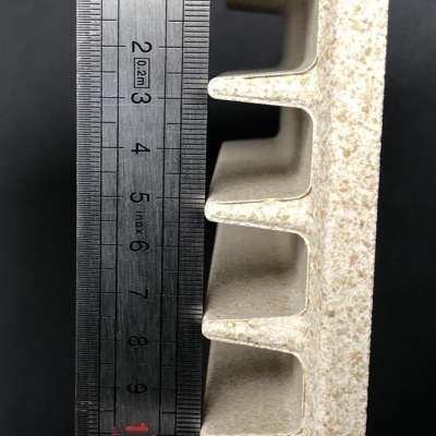 régua metálica ao lado de objeto branco com orifícios quadrados