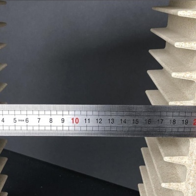 Régua metálica entre peças brancas com aletas sobre fundo preto.