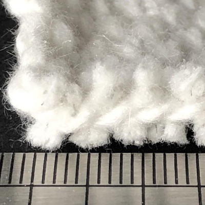 Close-up de malha branca grossa sobre régua metálica