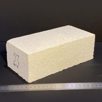 Bloco rectangular creme com textura rugosa e régua metálica ao lado