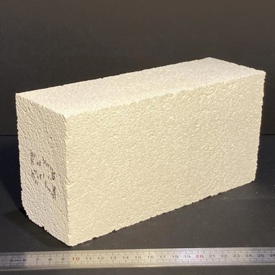 Bloco claro com textura rugosa e régua metálica em fundo escuro