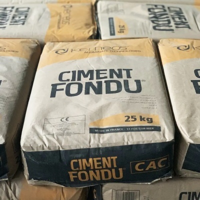 Sacos de cimento fundido Keimros em embalagem branca, amarela e azul, 25 kg cada.