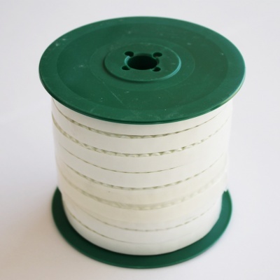 Carretel verde com fita branca enrolada, com textura e pequenas aberturas