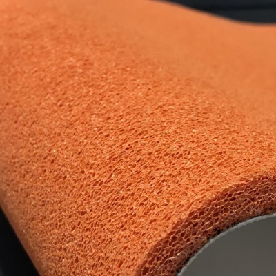 Esponja de banho laranja com textura porosa