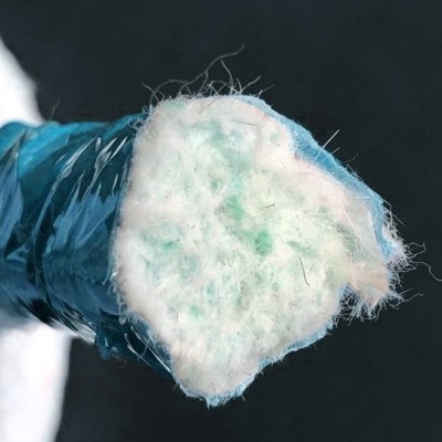 Mão com luva azul segurando material fibroso branco e azul.