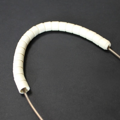 Cabo metálico com cobertura branca segmentada sobre fundo preto