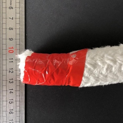 Rolo de fita adesiva vermelha em objeto branco ao lado de régua