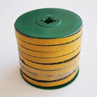 Carretel verde com fita adesiva amarela e linhas pretas