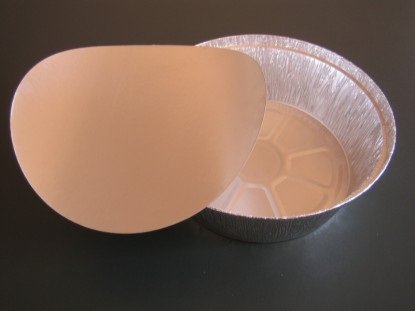 Embalagem redonda de alumínio com tampa branca sobre superfície preta