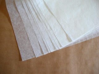 Folhas finas, transparentes e empilhadas sobre superfície castanha