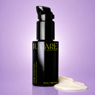 Frasco preto de creme hidratante com creme branco ao lado em fundo lilás