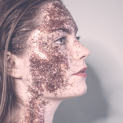 Rosto feminino com glitter cor de rosa cobre espalhado no rosto e pescoço