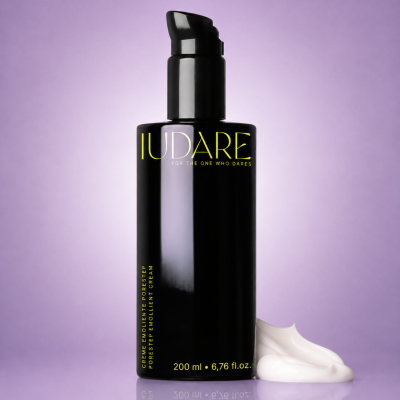Frasco preto de creme IUDARE com doseador, texto amarelo, creme branco ao lado, fundo lilás.
