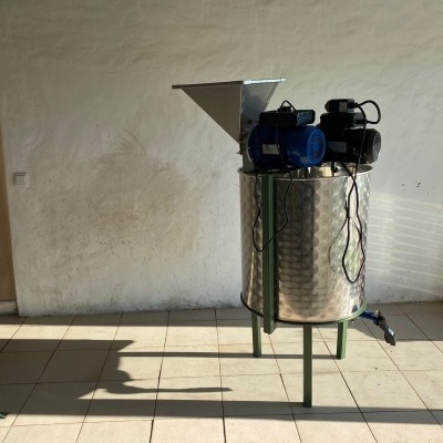 Máquina industrial de aço inoxidável com funil metálico e motores eléctricos em piso azulejado