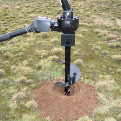 Broca de perfuração de solo preta metálica no chão com relva e terra