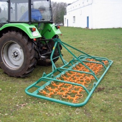 Trator verde com equipamento agrícola metálico laranja num campo