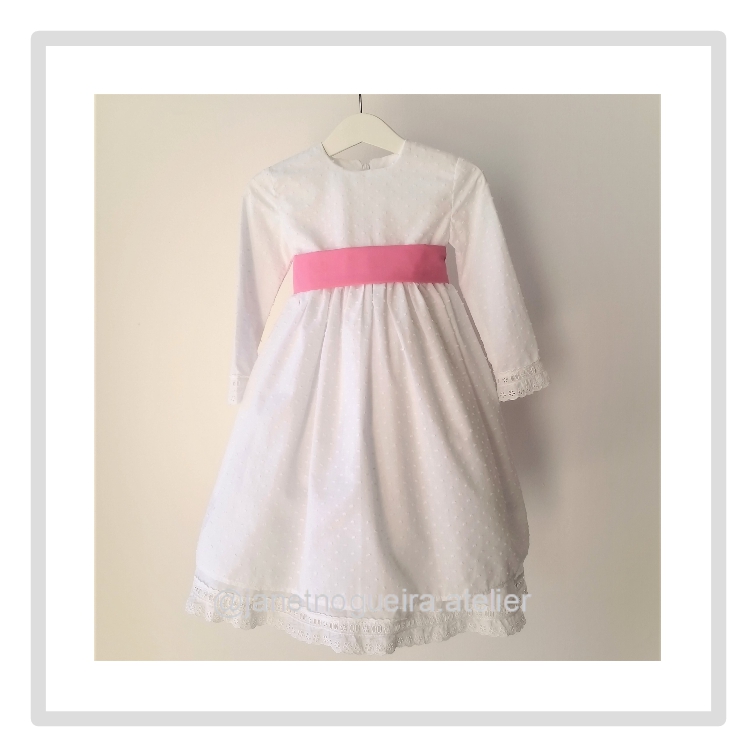 Vestido Iria Vestido branco infantil com faixa rosa pendurado