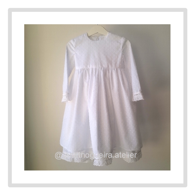 Vestido Iria Vestido infantil branco com renda e mangas compridas pendurado
