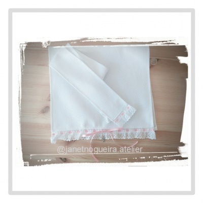 Conjunto branco de dois panos com borda em renda branca e rosa sobre madeira clara