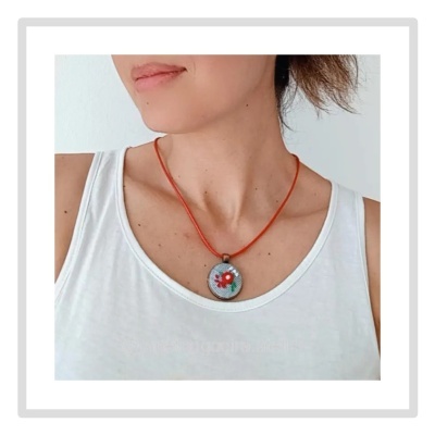 Colar com pendente redondo floral e cordão vermelho numa pessoa com camisola branca