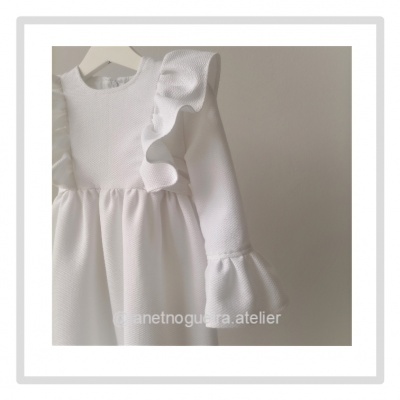 Vestido branco com folhos em tecido texturado pendurado num cabide