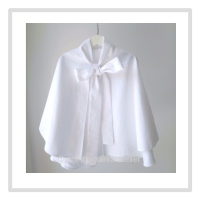 Capa branca feminina com laço frontal pendurada em cabide branco