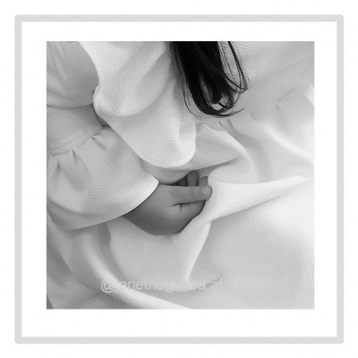 Bebé com vestido branco texturado a segurar o vestido com a mão