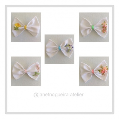 Cinco laços brancos com flores bordadas coloridas em fundo branco