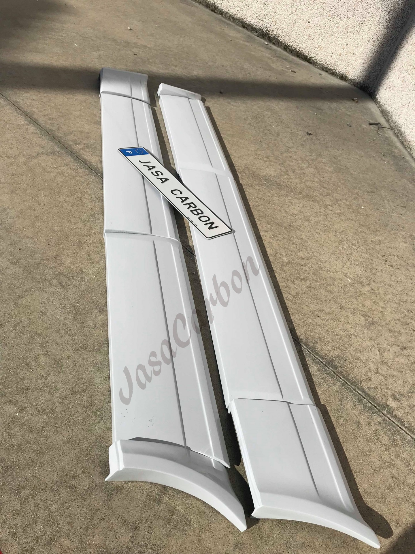 Par de frisos brancos com etiqueta JASA CARBON no chão perto da parede