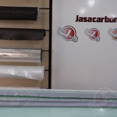 Três barras brancas sobre superfície azul clara com folhas enroladas ao fundo e texto Jasacarbon.com ao lado