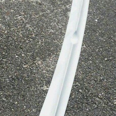 Componente automóvel branco longo sobre asfalto com texto vermelho Jasa Carbon.