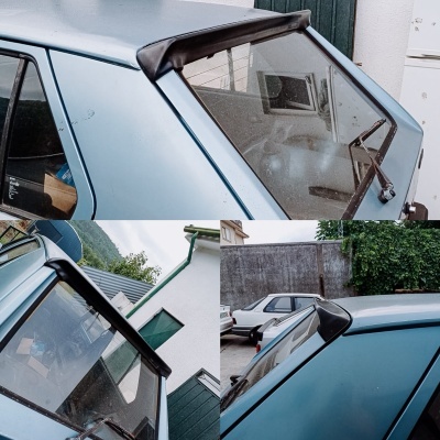 Spoiler traseiro preto em carro azul claro com limpa-vidros traseiro