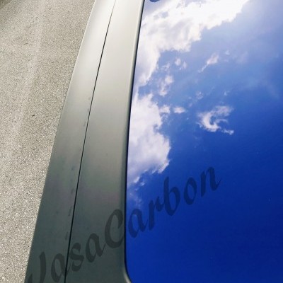 Spoiler traseiro preto em fibra de carbono sobre tampa de mala azul de carro