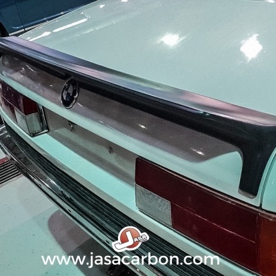 Para-choques traseiro branco de carro com spoiler preto, luzes vermelhas e texto www.jasacarbon.com
