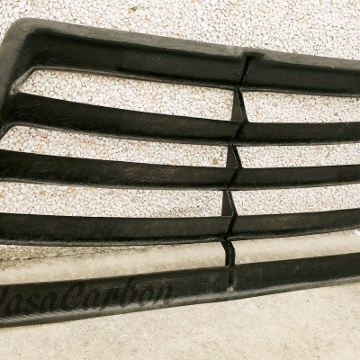 Grelha frontal de automóvel preta partida colocada no chão junto a uma parede