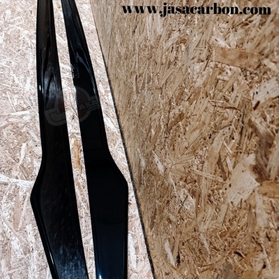 duas peças longas pretas de carbono apoiadas em chão e parede de madeira OSB com texto e logotipos JASA