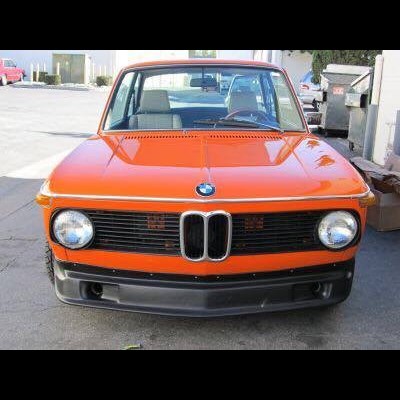 Automóvel vermelho laranja BMW clássico visto de frente