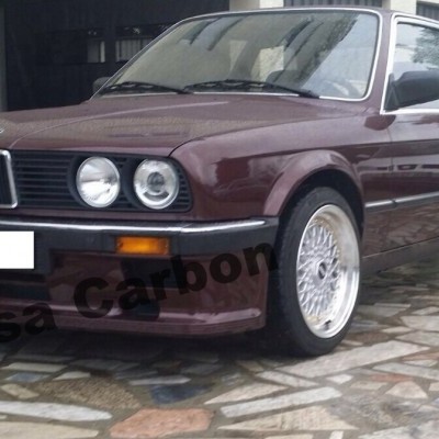 BMW coupe bordô com jantes prateadas estacionado em pavimento de pedra