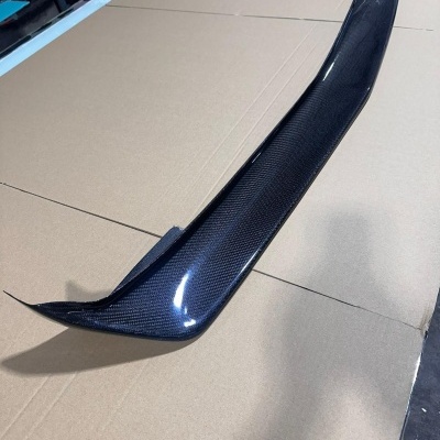 Spoiler de carro em fibra de carbono preta sobre superfície castanha