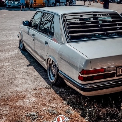 Carro sedan clássico prateado com rodas cromadas e persianas nas janelas traseiras