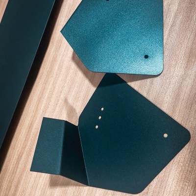 Peças metálicas pretas planas com orifícios sobre superfície de madeira clara