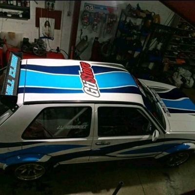 Carro desportivo branco e azul com texto GT turbo e GTI numa garagem