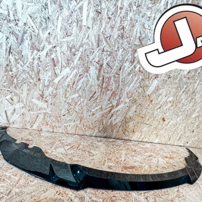 Peça automóvel preta com autocolante JASA Carbon contra parede de madeira