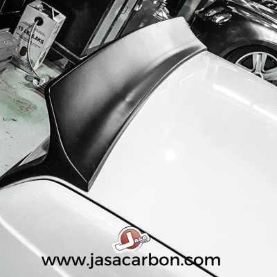 Parte traseira branca de carro com spoiler preto em oficina