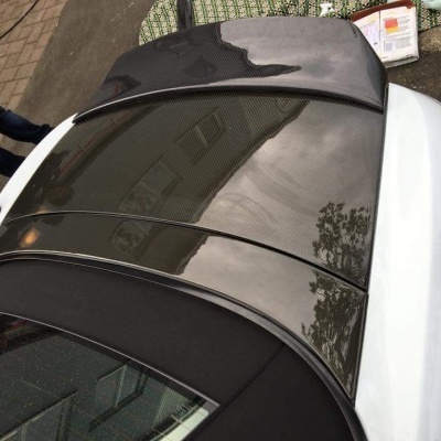 Carro branco com capota preta em rua com calçada de pedra