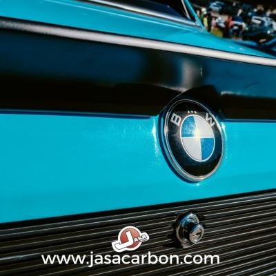 Emblema da BMW numa carroçaria azul com faixa preta e texto www.jasacarbon.com