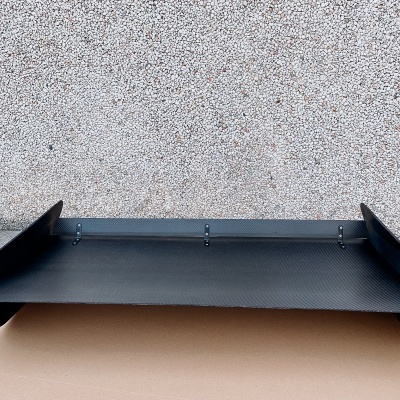 Prancha preta de fibra de carbono para automóvel contra parede cinza