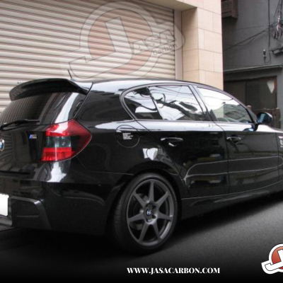 Carro BMW preto estacionado junto a edifício com porta de enrolar bege